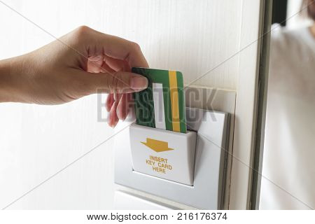 Female hand insert room card key to open electric light hotel room.