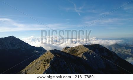 The mountain Lovcen in Montenegro. Capped mountains and fluffy white clouds below the peaks