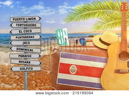 Concept of summer traveling with old suitcase and Costa Rica town sign with burning sun