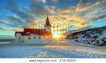 Typical red colored wooden church in Vik town, Iceland in winter. Sunrise light