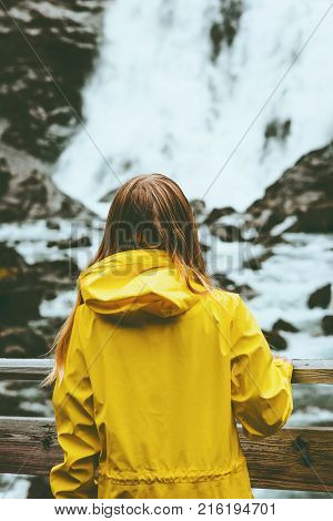 Tourist woman sightseeing waterfall outdoor Travel Lifestyle wanderlust concept adventure vacations in Norway wearing yellow raincoat clothing