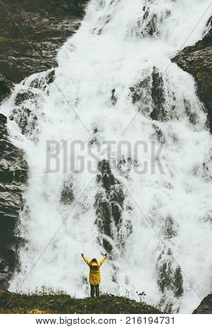 Woman traveler raised hands at big waterfall outdoor Travel Lifestyle success concept adventure vacations in wild nature