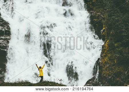 Woman adventurer happy raised hands enjoying big waterfall landscape outdoor Travel Lifestyle success concept adventure scandinavian vacations wild nature