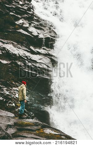 Man climbing rocky mountains with waterfall outdoor Travel Lifestyle success concept adventure scandinavian vacations extreme sport
