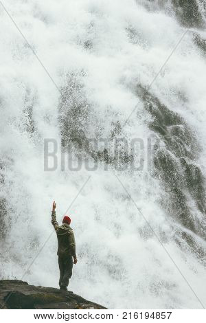 Happy Man standing on cliff at big waterfall outdoor Travel Lifestyle success concept adventure scandinavian vacations in Norway