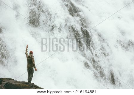 Traveler Man standing on cliff at big waterfall outdoor Travel Lifestyle success concept adventure scandinavian vacations power of nature