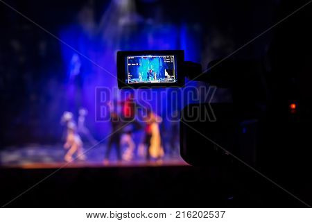 Filming the show from the auditorium. LCD viewfinder on the camcorder. Theatrical performance. The actors on stage. Out-of-focus background. The focus in the foreground.
