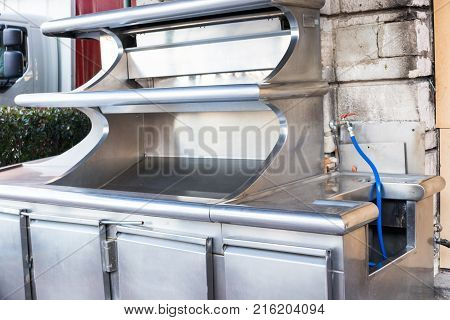 An empty restaurant workstand made of stainless steel is installed in the street.