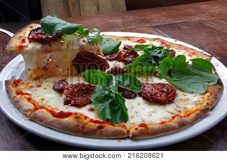 Pizza with mozzarella, rucula and dried tomato