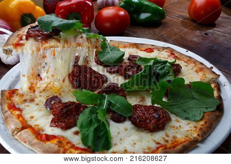 Pizza with mozzarella, rucula and dried tomato