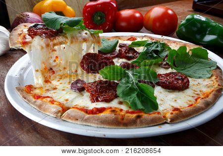 Pizza with mozzarella, rucula and dried tomato