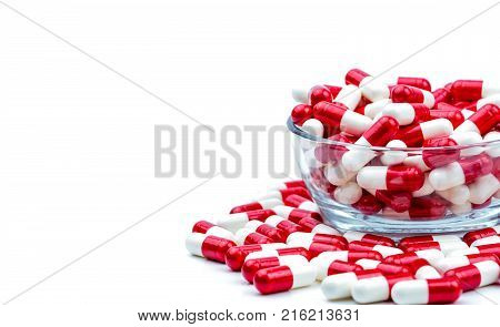 Red white antibiotic capsules pills in glass bowl and some on white background with copy space. Drug resistance concept. Antibiotics drug use with reasonable and global healthcare concept.