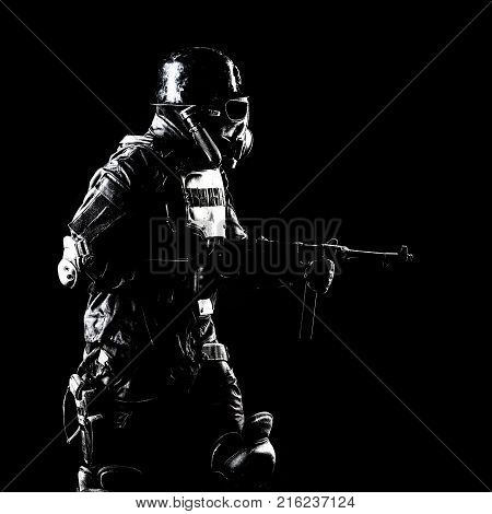 Futuristic nazi soldier gas mask and steel helmet with schmeisser handgun black background studio shot