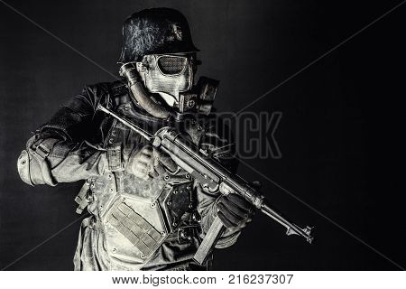 Futuristic nazi soldier gas mask and steel helmet with schmeisser handgun black background studio shot