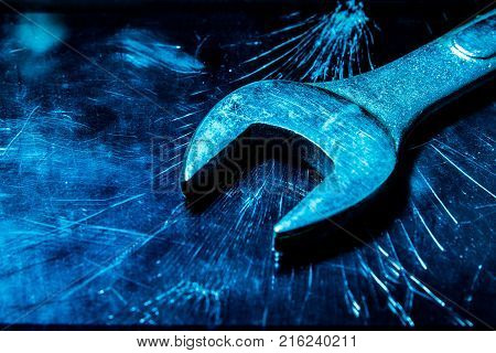 a wrench on the background of a broken tablet. blue tinting