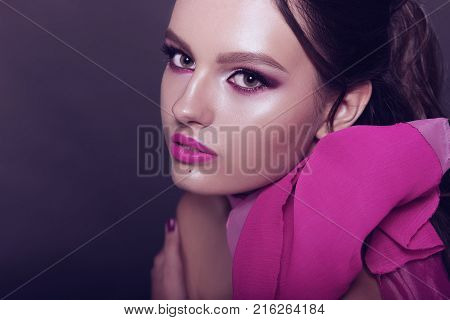 Beautiful Fashionable Girl Haired With Long Curly Hair Posing With A Pink Bow. The Girl In The Studi