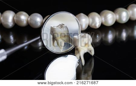 bad rotten tooth pulled and stands opposite the offices of the mirrors and dazzling white pearls on a black isolated background