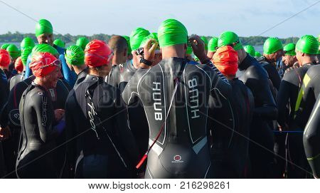 GRAFHAM, CAMBRIDGESHIRE, ENGLAND - MAY 21, 2017:  Competitors waiting to start the open water stage wearing swimming caps and wet suits at the  beginning of Triathlon.