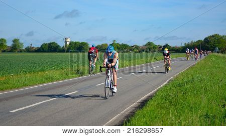 GRAFHAM, CAMBRIDGESHIRE, ENGLAND - MAY 22, 2016:  Triathletes on road cycling stage of triathlon riding in both directions.