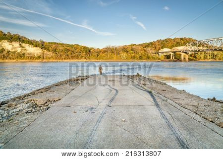 Lonely figure at the end of boat ramp on Missouri River at Taylor's Landing  near Rocheport, MO, fall colors scenery