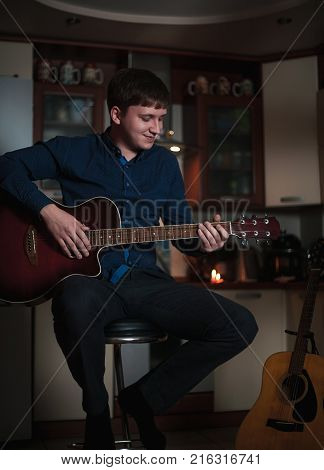 The Guitarist Guy plays the guitar in a bar in a beautiful setting on a high bar stool