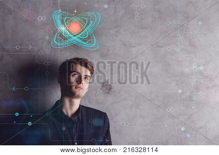 Thoughtful young european businessman with digital atom on concrete background with circuit and copyspace. Technology and innovation concept. Double exposure