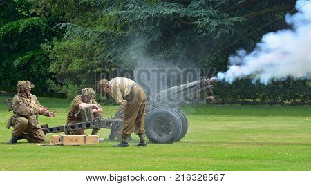 SILSOE, BEDFORDSHIRE, ENGLAND - MAY 28, 2017:  Second World War Field Gun Being Fired gunners wearing Uniforms.