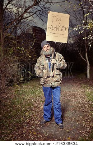 Older homeless man looking for something to eat