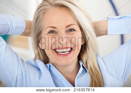 Modern businesswoman. Beautiful middle aged woman looking at camera with smile while siting in the office. Female face close-up