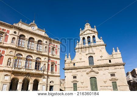 The town hall and the mother church built at the end of the 17th century in the baroque town of Grammichele against a blue sky in the Catania province of Sicily in Italy