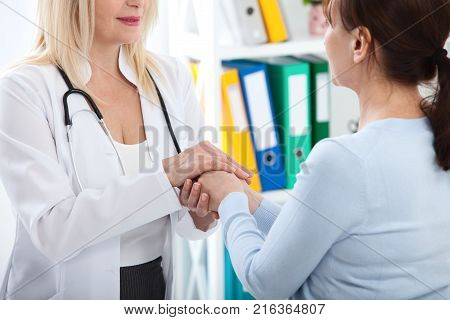 Hand of doctor reassuring her female patient. Medical ethics and trust concept