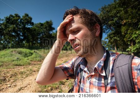 Tired Man in forest unfder strong sun with backpack. Travel in Asia alone. Suffer form sunstroke. lifestyle concept of adventure and summer vacations