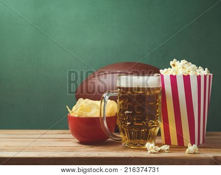 American football watching concept with beer pop corn and chips over green background