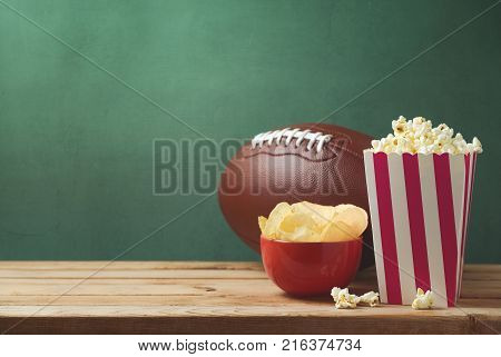 American football watching concept with pop corn and chips over green background