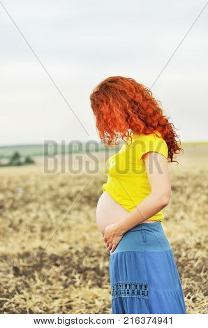 Pregnant woman. Pregnancy. 
Young pragnant woman on field