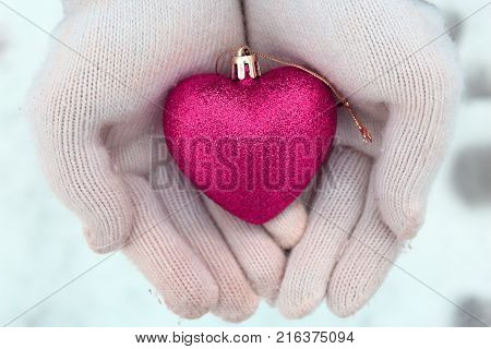 A heart in the palms. White mittens and heart. Heart on the snow. The spirit of Christmas. Christmas traditions. Winter mood. Valentine's day. Love and feelings. Pink heart