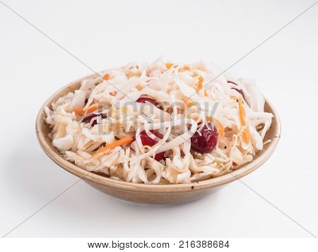 Traditional russian appetizer sauerkraut with cranberry and carrot in craft plate isolated on white. Fermented cabbage. Russian cuisine and russian kitchen.