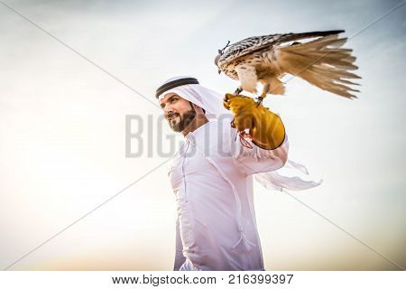 Arabian man walking in the desert at sunrise