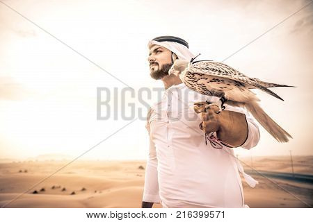 Arabian man walking in the desert at sunrise