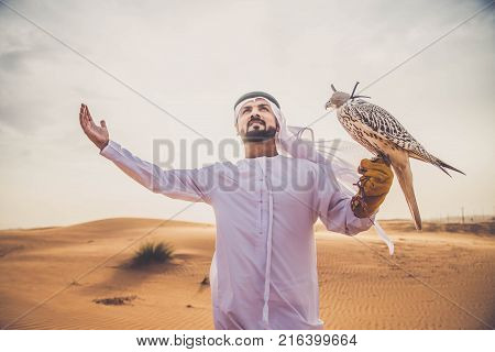 Arabian man walking in the desert at sunrise