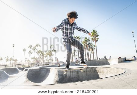 Cool skateboarder outdoors - Afroamerican guy jumping with his skate and performing a trick