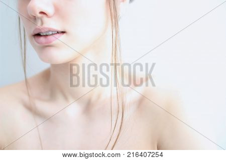 Women's chin lips and collarbone in a high key on a white background