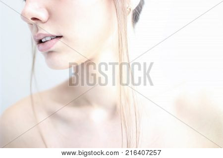 Women's chin lips and collarbone in a high key on a white background