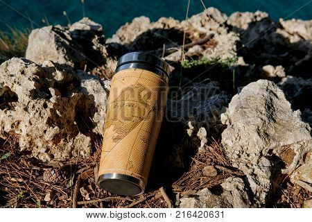 Closeup photo of thermos mug with tea over sea view