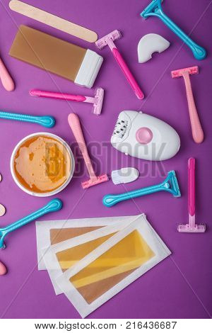 Female epilator, disposable razor, wax strips, wax, wax in a cassette, scattered and lie on a bright pink background, top view.