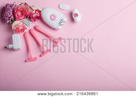 Close-up of a female epilator and four disposable pink razors with roses, lie on a pink background, top view, free space for text.