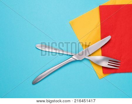 Fork knife and colored napkin on blue background. Food theme composition