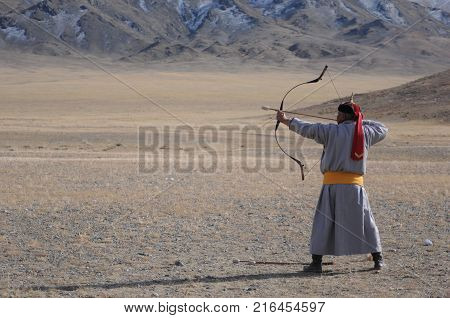 old man dressed with traditional mongolian costume compete in a boe and arrow contest during the golden eagle festival in mongolia