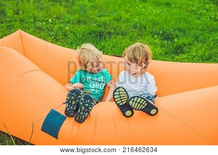 Two cute boys resting on an air sofa in the park.. lamzac