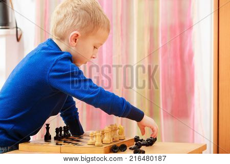 Intelligent smart ass kids games good for brain intelligence concept. Young kid boy playing chess and having fun.